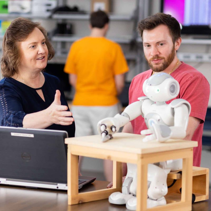 Lynne Parker looks at a robot in a lab with a student