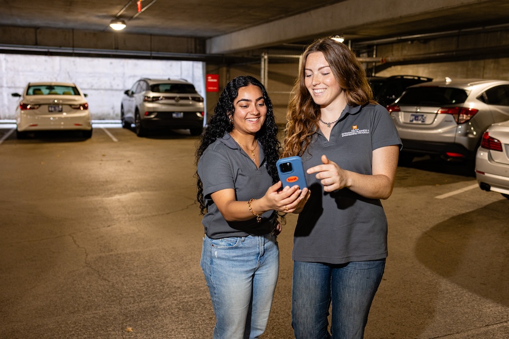 female students using the VolPark app on their phone in a parking garage