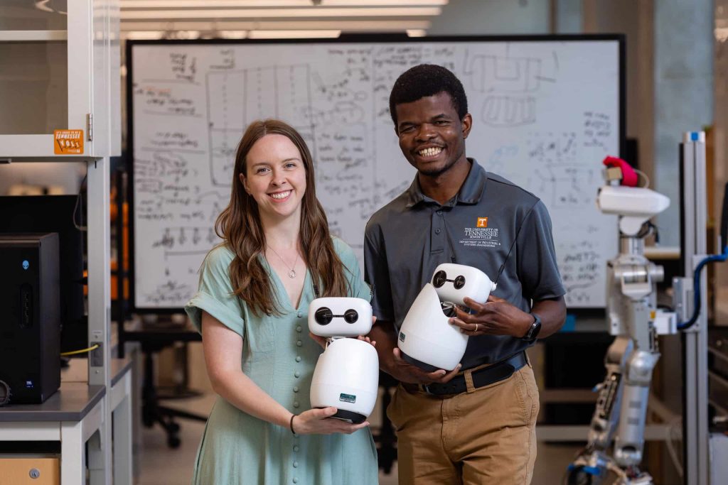 Samuel Olatunji and Rachael Bevill Burns each hold a robot