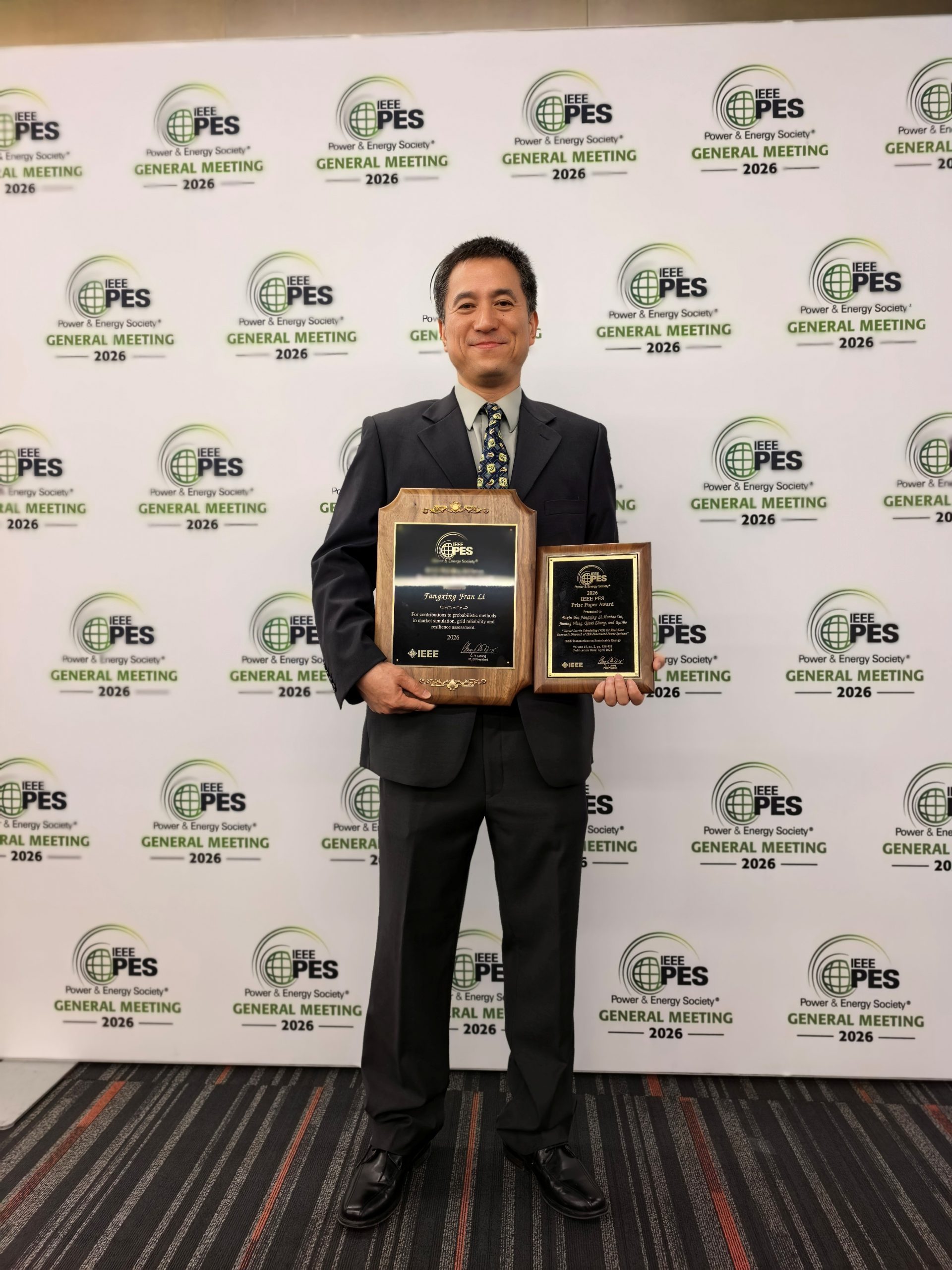 Fran Li holding his Billinton Award and Prize Paper Award plaques