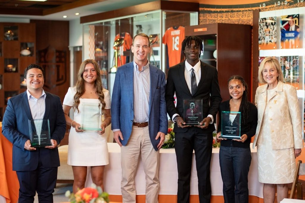 Peyton Manning and Chancellor Donde Plowman standing with the 2026 scholarship recipients