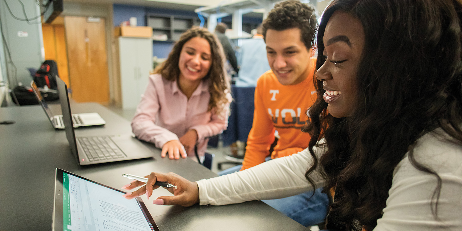 computer science students working on a project together while looking at a tablet